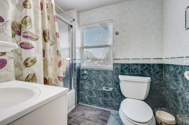 bathroom with shower / bath combination with glass door, toilet, tile walls, and vanity