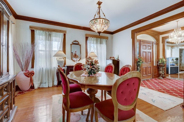 dining room with an inviting chandelier, ornamental molding, and light wood finished floors