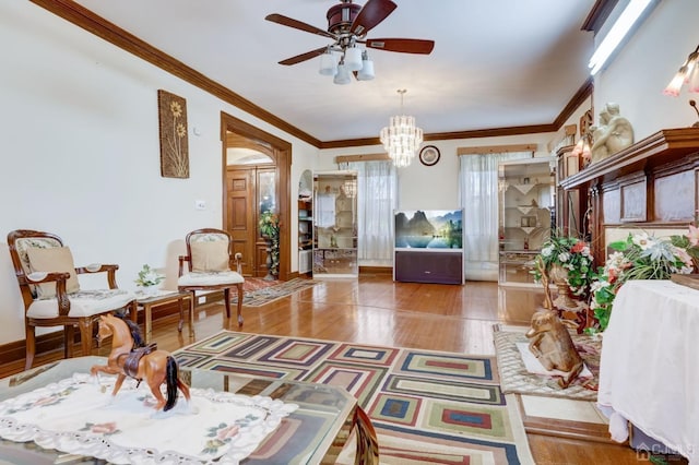 sitting room featuring ceiling fan with notable chandelier, wood finished floors, baseboards, and ornamental molding