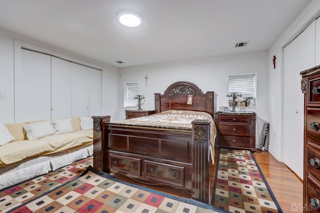 bedroom featuring light wood-type flooring, visible vents, and a closet