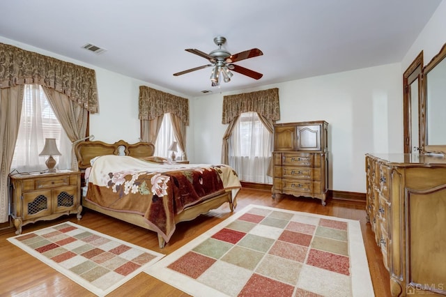 bedroom featuring baseboards, wood finished floors, visible vents, and ceiling fan