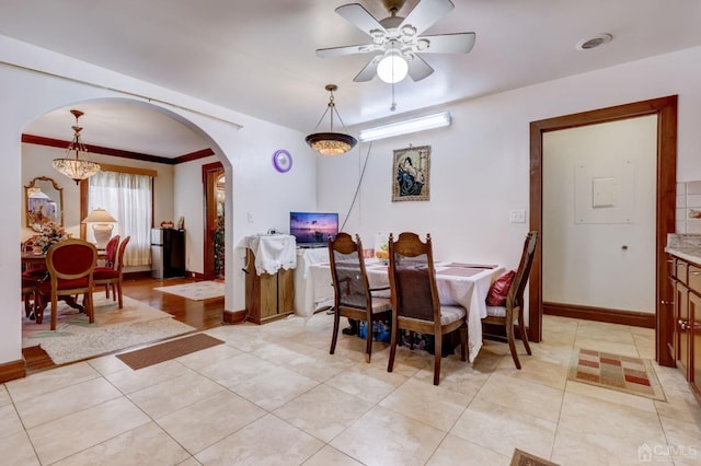 dining area with light tile patterned floors, baseboards, an inviting chandelier, arched walkways, and ornamental molding