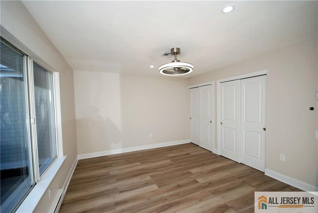 unfurnished bedroom featuring two closets and wood-type flooring