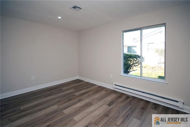 spare room featuring a wealth of natural light, dark hardwood / wood-style floors, and a baseboard heating unit