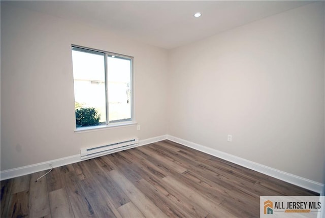 unfurnished room featuring a baseboard heating unit and hardwood / wood-style floors