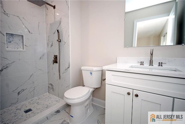 bathroom featuring a tile shower, vanity, and toilet