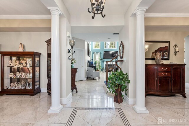 foyer with decorative columns, crown molding, and a notable chandelier