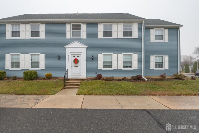 colonial-style house featuring a front lawn