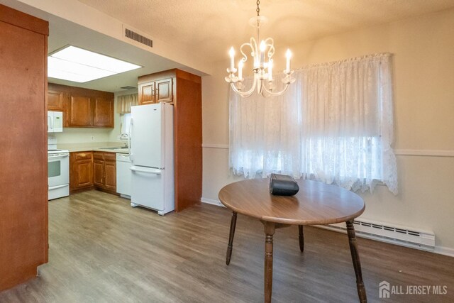 kitchen with pendant lighting, white appliances, an inviting chandelier, sink, and baseboard heating