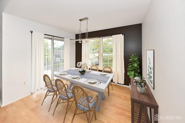 dining room featuring light wood-type flooring, baseboards, and a wealth of natural light