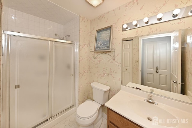 bathroom featuring vanity, wallpapered walls, a stall shower, tile patterned floors, and toilet