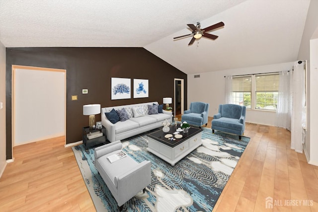 living room featuring light wood-style flooring, a ceiling fan, visible vents, lofted ceiling, and baseboards