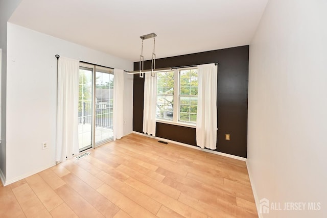 unfurnished room with visible vents, light wood-style flooring, and baseboards