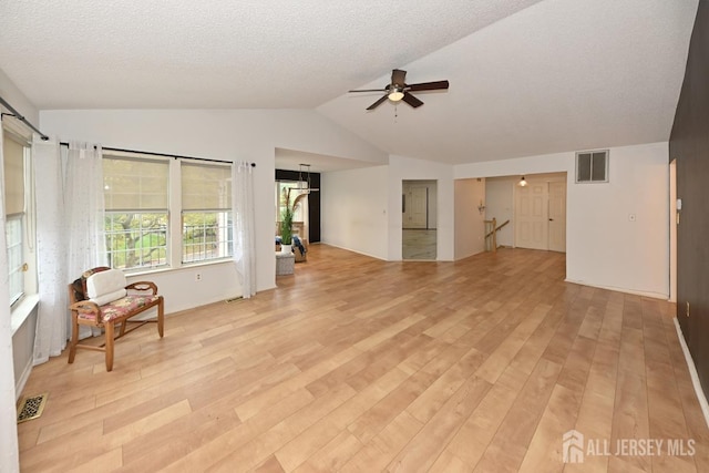 living area with lofted ceiling, ceiling fan, light wood-style flooring, and visible vents