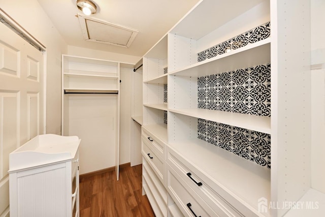 walk in closet with attic access and wood finished floors