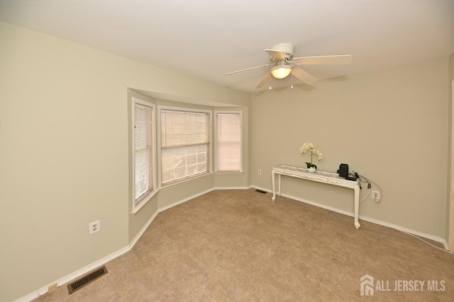 carpeted empty room featuring a ceiling fan, visible vents, and baseboards