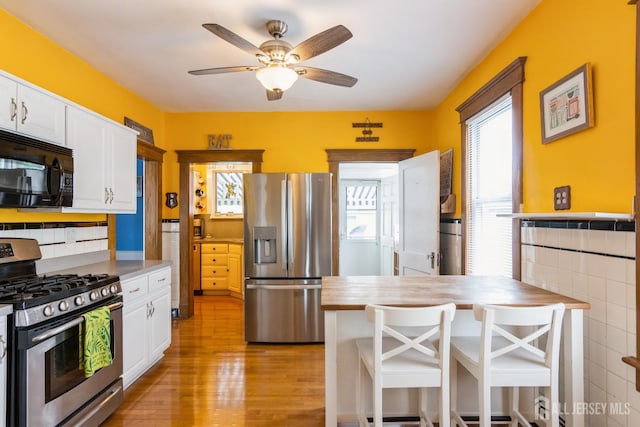 177 Hillside Ave, South River, NJ 08882 - kitchen featuring appliances with stainless steel finishes, white cabinetry, light wood-style floors, a ceiling fan, and a breakfast bar