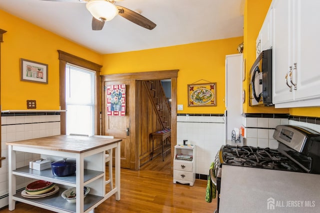 177 Hillside Ave, South River, NJ 08882 - kitchen featuring black microwave, stainless steel range with gas stovetop, tile walls, light wood-style flooring, and ceiling fan