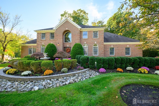 colonial house featuring a front lawn and brick siding