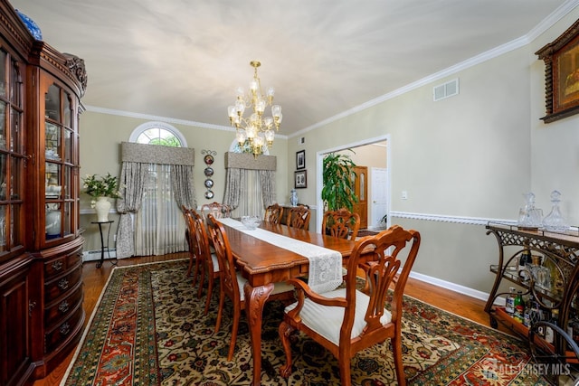 dining area featuring an inviting chandelier, crown molding, visible vents, and wood finished floors