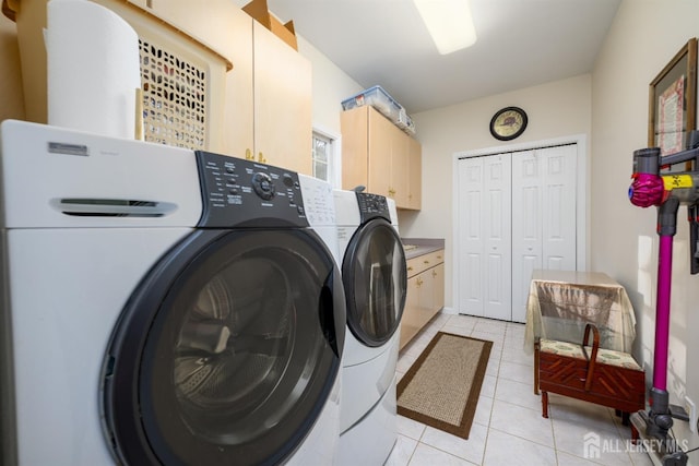 laundry area featuring washer and clothes dryer, light tile patterned flooring, and cabinet space