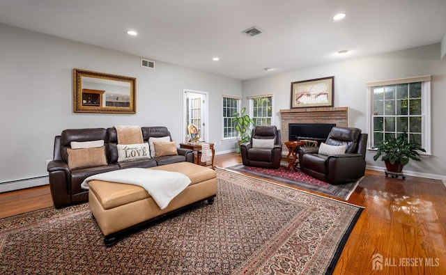 living area featuring a brick fireplace, wood finished floors, visible vents, and recessed lighting