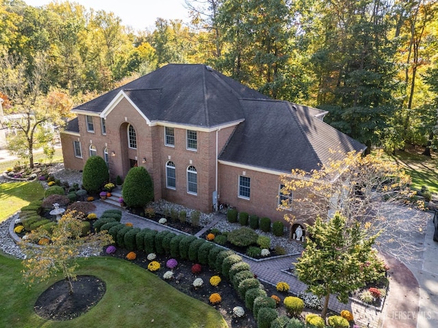 view of front of home featuring a shingled roof, a front yard, and brick siding