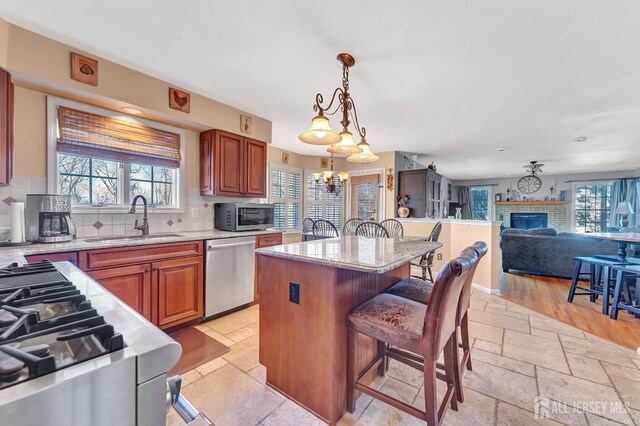 kitchen with sink, hanging light fixtures, stainless steel appliances, a kitchen breakfast bar, and a center island