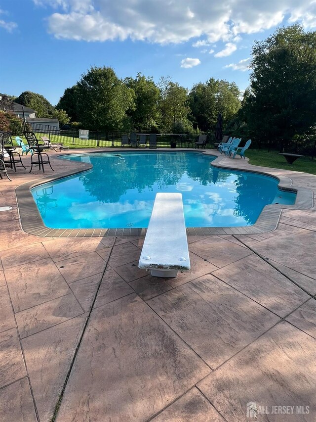 view of pool featuring a diving board and a patio