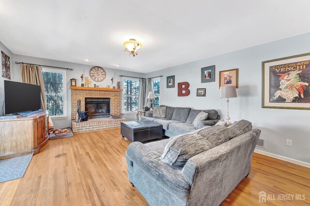 living room featuring hardwood / wood-style flooring and a brick fireplace