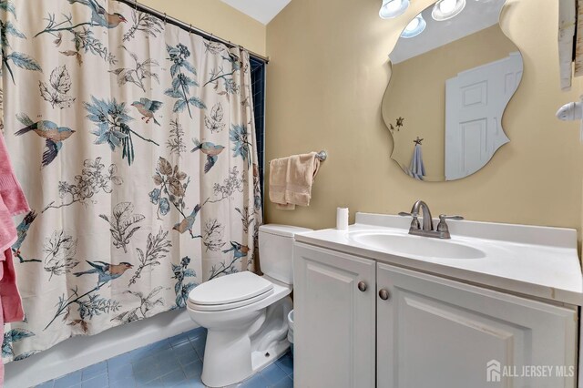 bathroom with a shower with curtain, vanity, tile patterned floors, and toilet