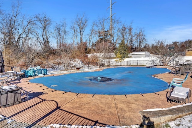 snow covered pool featuring a diving board and a patio