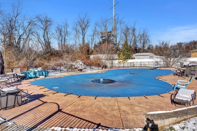 snow covered pool with a diving board and a patio area