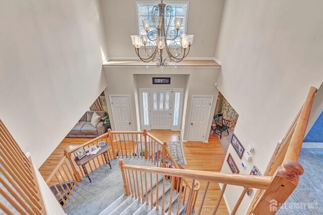 foyer with an inviting chandelier, a towering ceiling, and hardwood / wood-style flooring