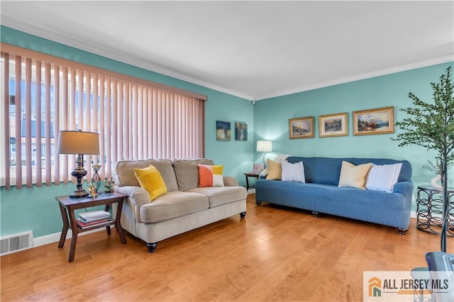 living room with visible vents, wood finished floors, and ornamental molding