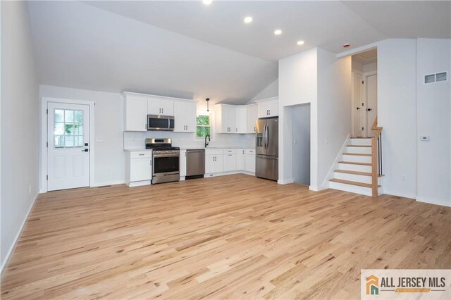 kitchen featuring stainless steel appliances, vaulted ceiling, light wood finished floors, plenty of natural light, and recessed lighting