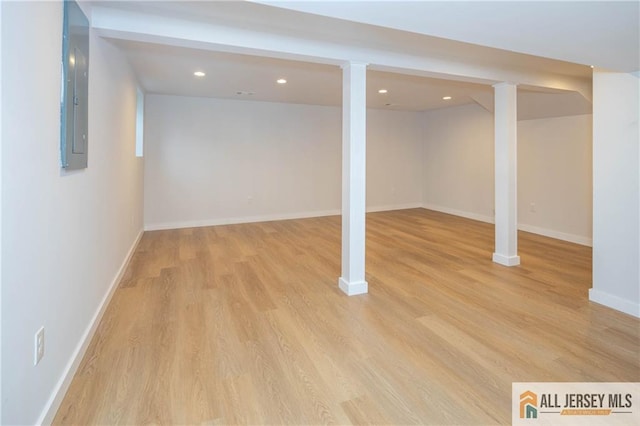 finished basement with light wood-style flooring, baseboards, recessed lighting, and electric panel