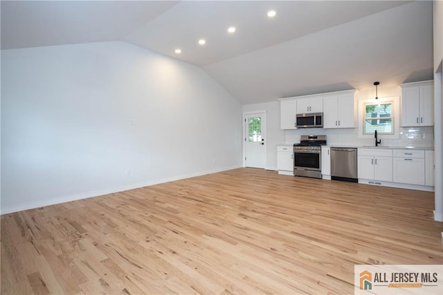 unfurnished living room with a sink, lofted ceiling, light wood-style floors, recessed lighting, and baseboards