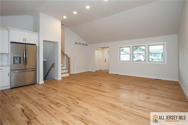 unfurnished living room featuring lofted ceiling, light wood-style flooring, recessed lighting, baseboards, and stairs