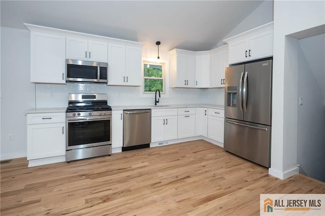 kitchen featuring stainless steel appliances, a sink, light countertops, backsplash, and white cabinets