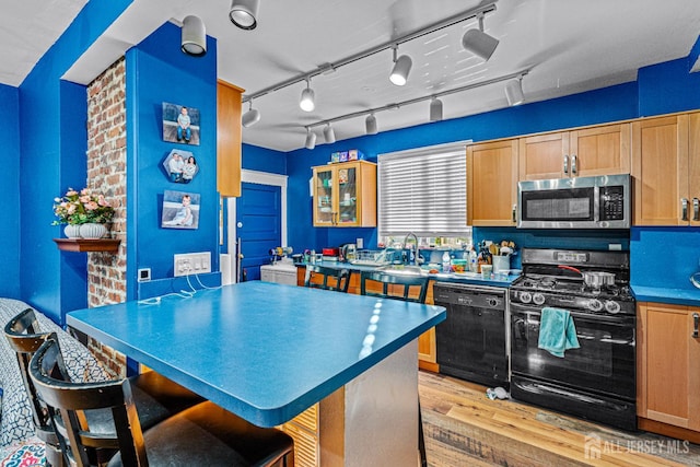 55 Suydam St, New Brunswick, NJ 08901 - kitchen featuring black appliances, light wood-style flooring, a sink, a breakfast bar area, and glass insert cabinets