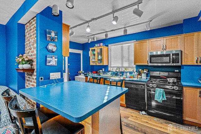 55 Suydam St, New Brunswick, NJ 08901 - kitchen with black appliances, light wood-type flooring, a breakfast bar, glass insert cabinets, and light brown cabinets