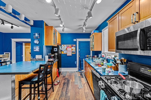 55 Suydam St, New Brunswick, NJ 08901 - kitchen featuring black range with gas stovetop, stainless steel microwave, rail lighting, a sink, and wood finished floors