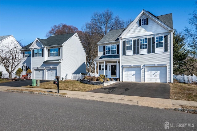 traditional home with a garage, aphalt driveway, and fence