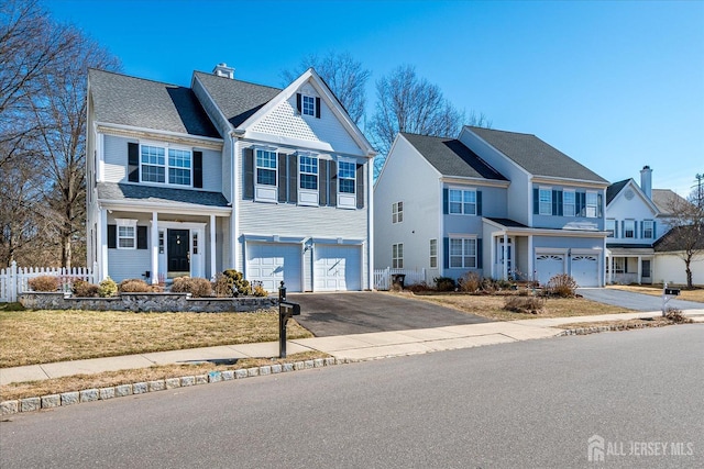 view of front of home featuring driveway, a chimney, an attached garage, fence, and a front yard