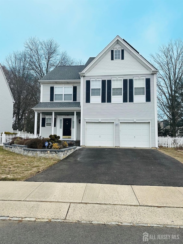 traditional-style house with driveway, an attached garage, and fence