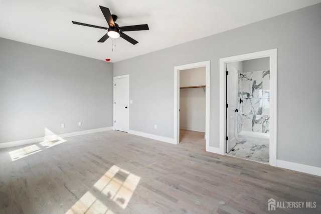 unfurnished bedroom with ensuite bathroom, ceiling fan, a spacious closet, light hardwood / wood-style floors, and a closet