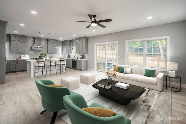 living room featuring ceiling fan, light hardwood / wood-style flooring, and a healthy amount of sunlight