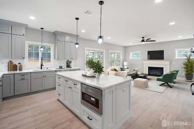 kitchen with gray cabinetry, sink, ceiling fan, decorative backsplash, and built in microwave