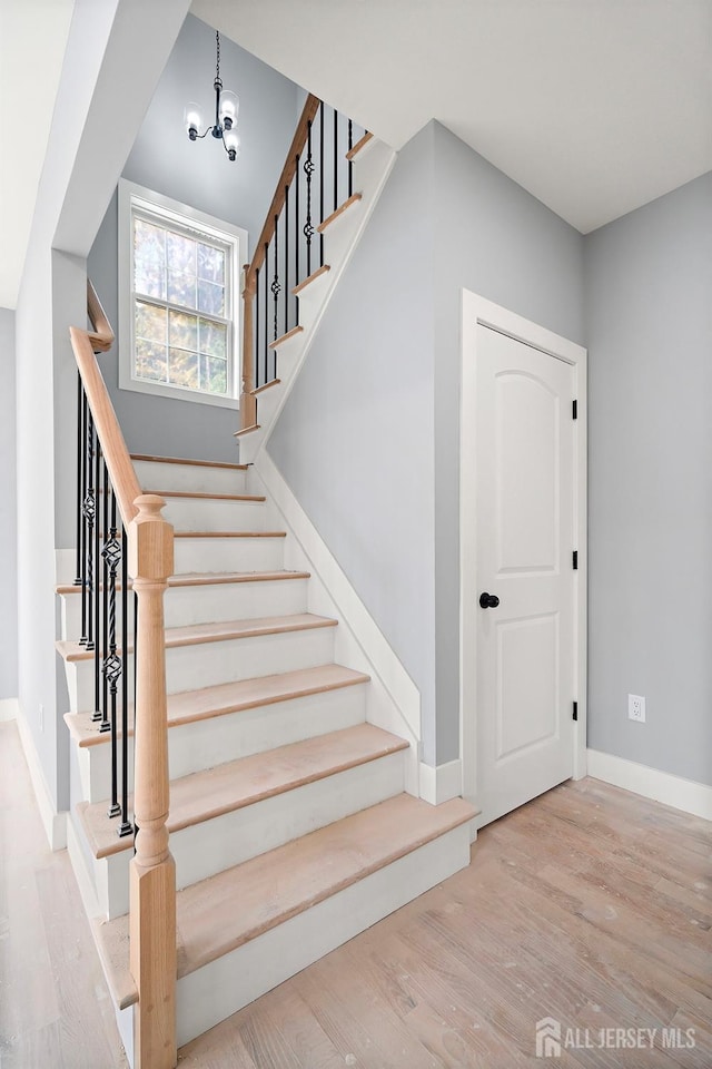 stairway featuring hardwood / wood-style floors and a chandelier